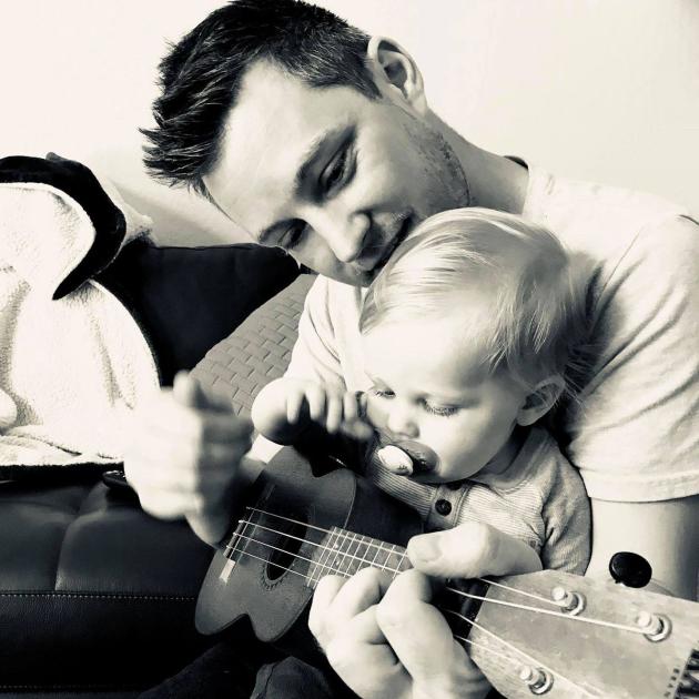 Tim playing guitar with baby