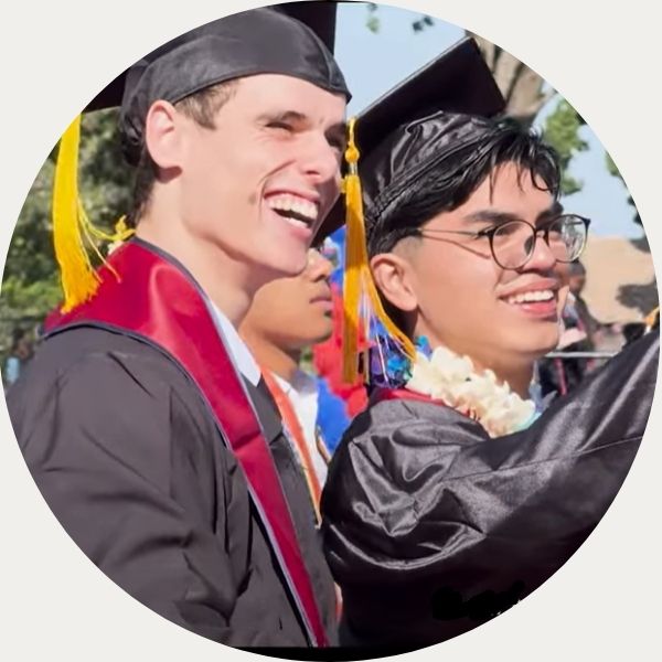 Two male graduates looking into the crowd and smiling